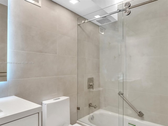 bathroom featuring tile walls, vanity, and combined bath / shower with glass door