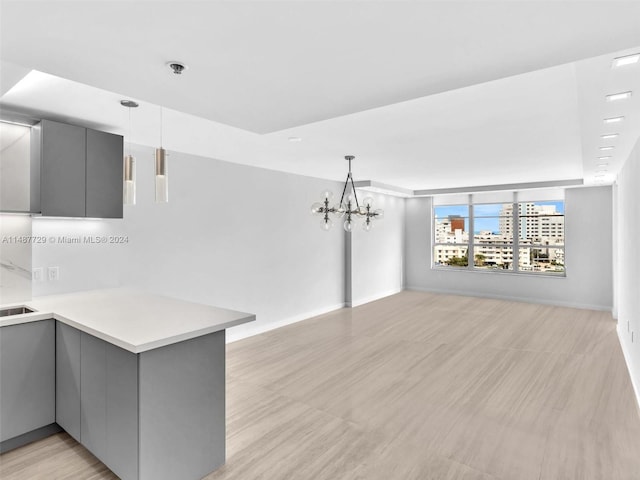 kitchen featuring a chandelier, gray cabinetry, pendant lighting, and kitchen peninsula