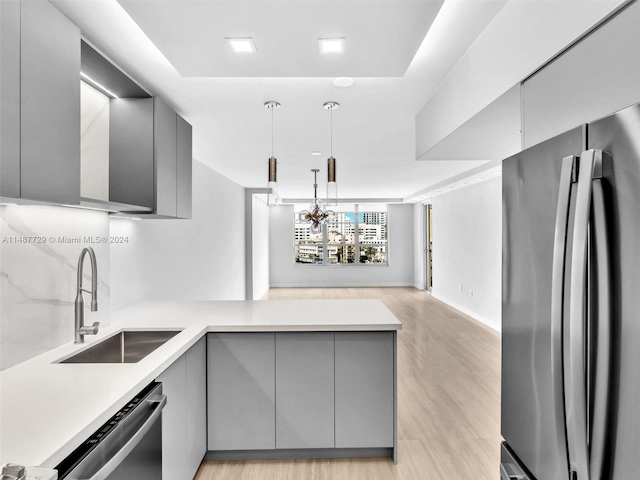 kitchen with sink, decorative light fixtures, appliances with stainless steel finishes, light hardwood / wood-style floors, and gray cabinetry