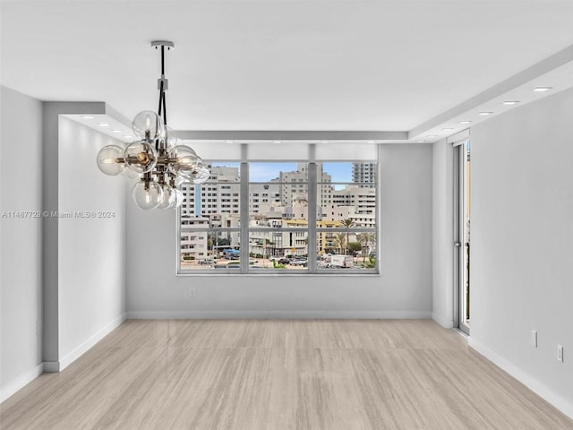 empty room featuring light hardwood / wood-style floors and a chandelier