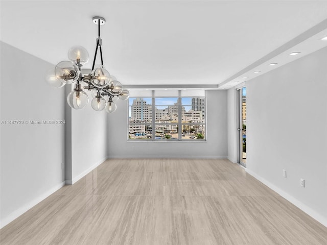 empty room featuring an inviting chandelier and light hardwood / wood-style flooring