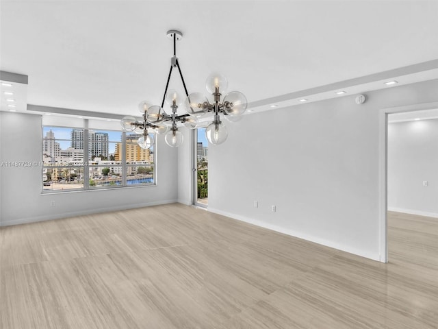 spare room with light hardwood / wood-style flooring and an inviting chandelier