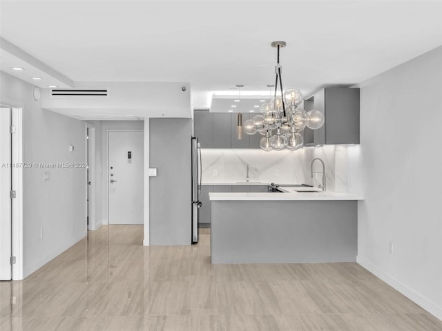 kitchen with tasteful backsplash, stainless steel refrigerator, gray cabinetry, pendant lighting, and light tile floors