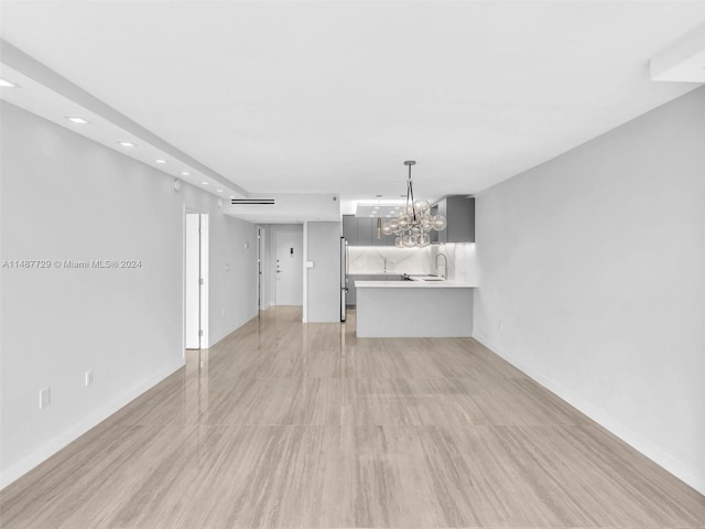 unfurnished living room featuring sink and a chandelier