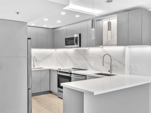 kitchen featuring tasteful backsplash, gray cabinets, stainless steel appliances, and decorative light fixtures