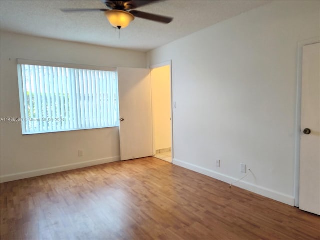 spare room with a textured ceiling, light wood-type flooring, and ceiling fan