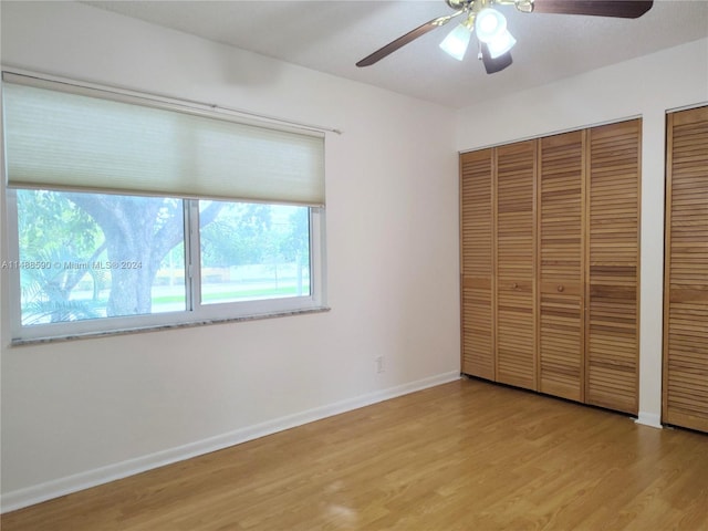 unfurnished bedroom featuring two closets, light hardwood / wood-style flooring, and ceiling fan