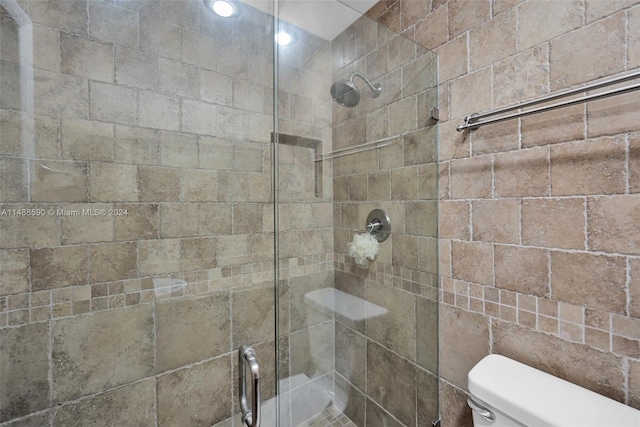 bathroom featuring toilet and a shower with shower door