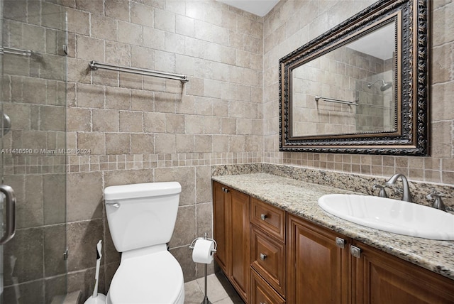 bathroom featuring a shower with door, vanity, tile walls, and toilet