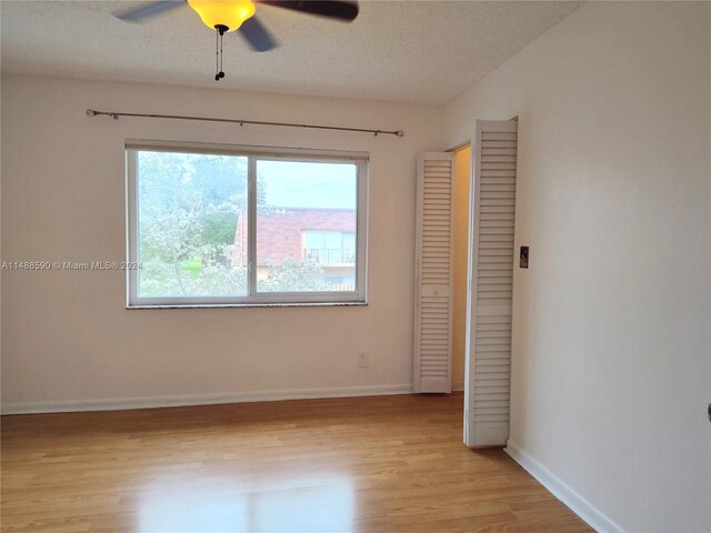 spare room featuring ceiling fan, light hardwood / wood-style flooring, and a textured ceiling