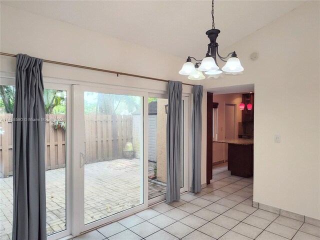 unfurnished dining area featuring a notable chandelier, light tile patterned floors, and lofted ceiling