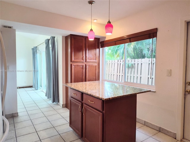 kitchen with light stone countertops, a center island, hanging light fixtures, and light tile patterned flooring