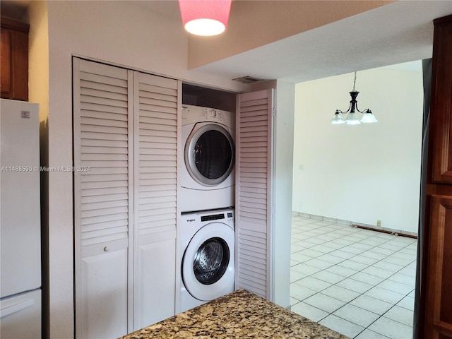 laundry room with light tile patterned floors and stacked washer and dryer