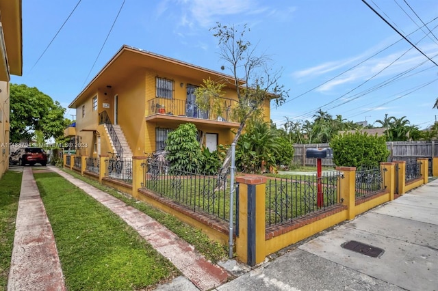 view of front of home featuring a balcony and a front yard