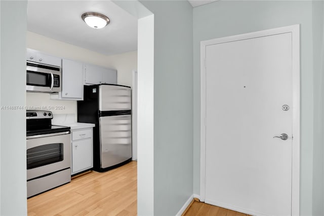 kitchen with white cabinets, appliances with stainless steel finishes, and light hardwood / wood-style floors