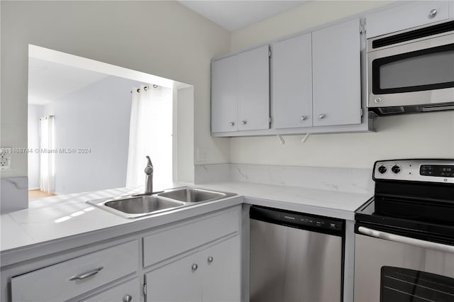 kitchen featuring stainless steel appliances, white cabinetry, and sink