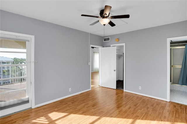 unfurnished bedroom featuring a walk in closet, light tile flooring, and ceiling fan