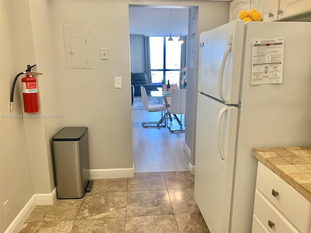 kitchen with white cabinets, light tile floors, and white fridge