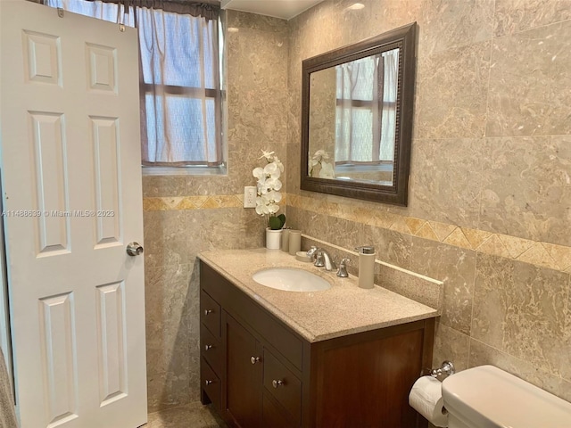 bathroom featuring vanity, toilet, and tile walls