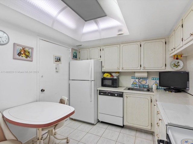 kitchen with light tile floors, cream cabinetry, white appliances, and sink