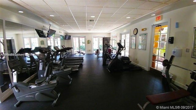 exercise room with a drop ceiling and a healthy amount of sunlight