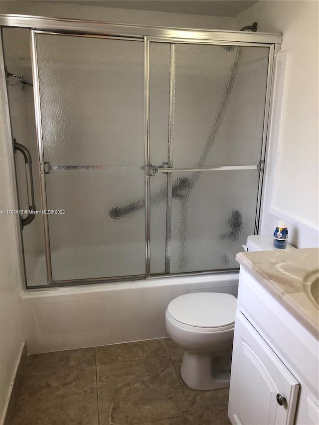 full bathroom featuring vanity, tile floors, shower / bath combination with glass door, and toilet