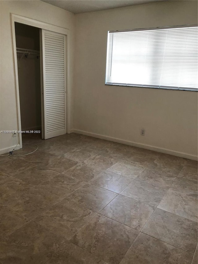 unfurnished bedroom featuring a closet and light tile floors