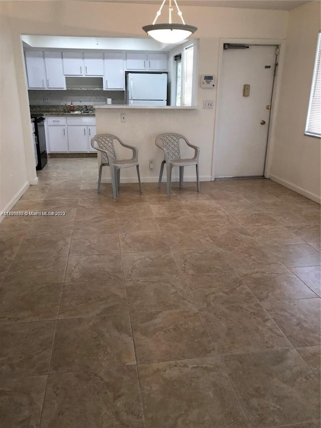 kitchen with white cabinets, light tile floors, white fridge, and range