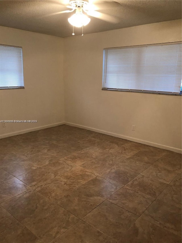 tiled spare room featuring ceiling fan and a textured ceiling