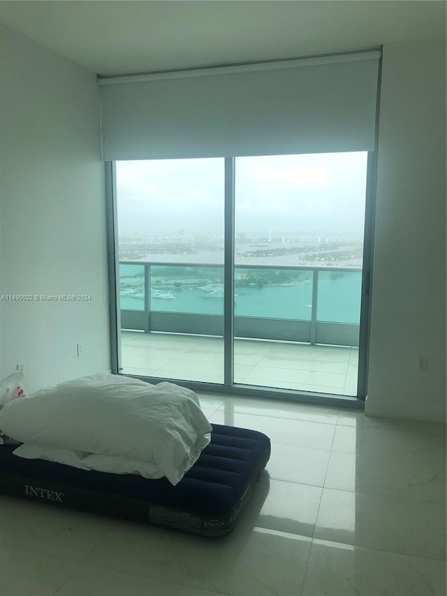 bedroom with light tile floors and a wall of windows