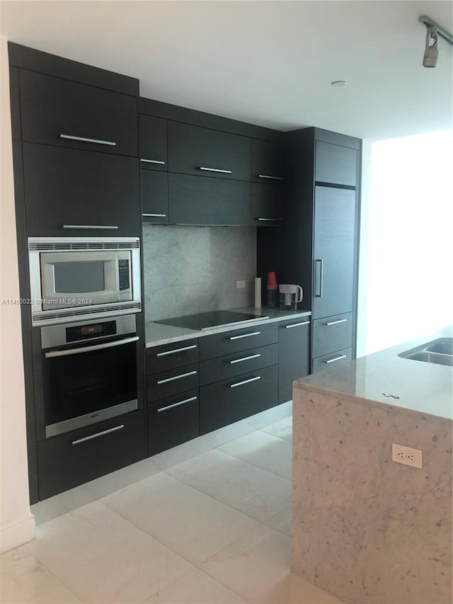 kitchen featuring backsplash, appliances with stainless steel finishes, light tile floors, and light stone counters