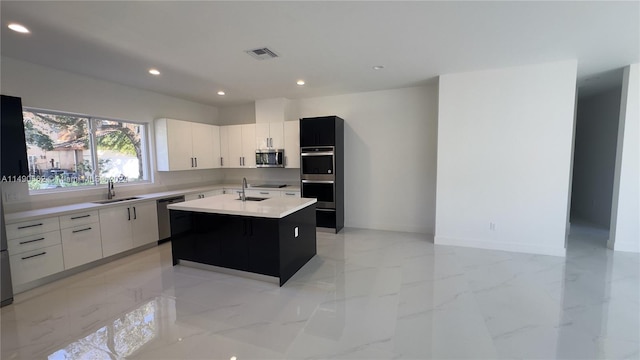 kitchen with light tile flooring, stainless steel appliances, a kitchen island with sink, and sink