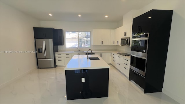 kitchen with a kitchen island with sink, light tile floors, appliances with stainless steel finishes, and sink