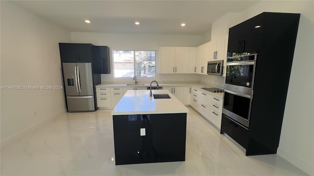 kitchen with light tile floors, an island with sink, sink, and stainless steel appliances