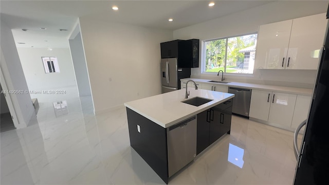 kitchen with an island with sink, appliances with stainless steel finishes, light tile floors, and sink