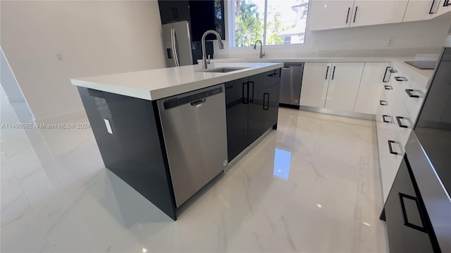 kitchen featuring white cabinetry, light tile flooring, appliances with stainless steel finishes, sink, and a center island with sink