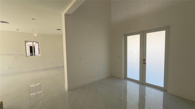 tiled spare room featuring plenty of natural light and french doors