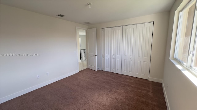 unfurnished bedroom featuring dark carpet and a closet