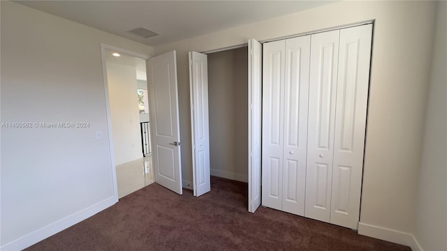 unfurnished bedroom featuring a closet and dark carpet