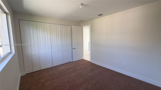 unfurnished bedroom featuring a closet and dark carpet