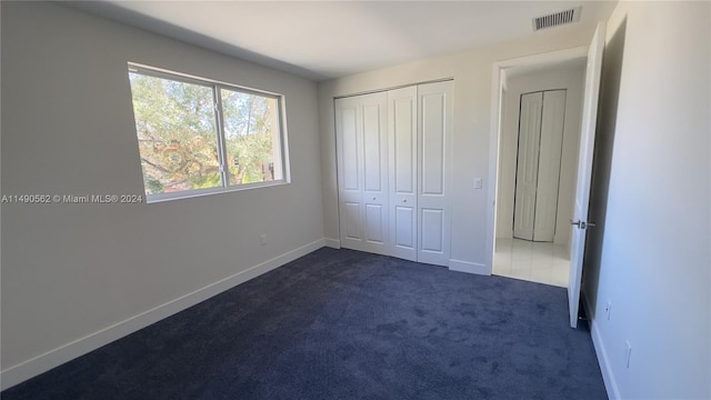 unfurnished bedroom featuring dark carpet and a closet