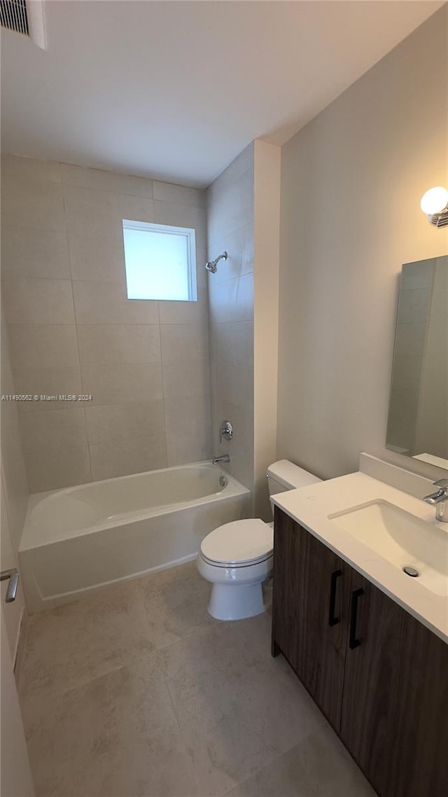 full bathroom with toilet, vanity with extensive cabinet space, tile floors, and tiled shower / bath combo