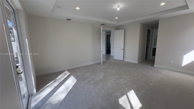 empty room with light carpet and a tray ceiling