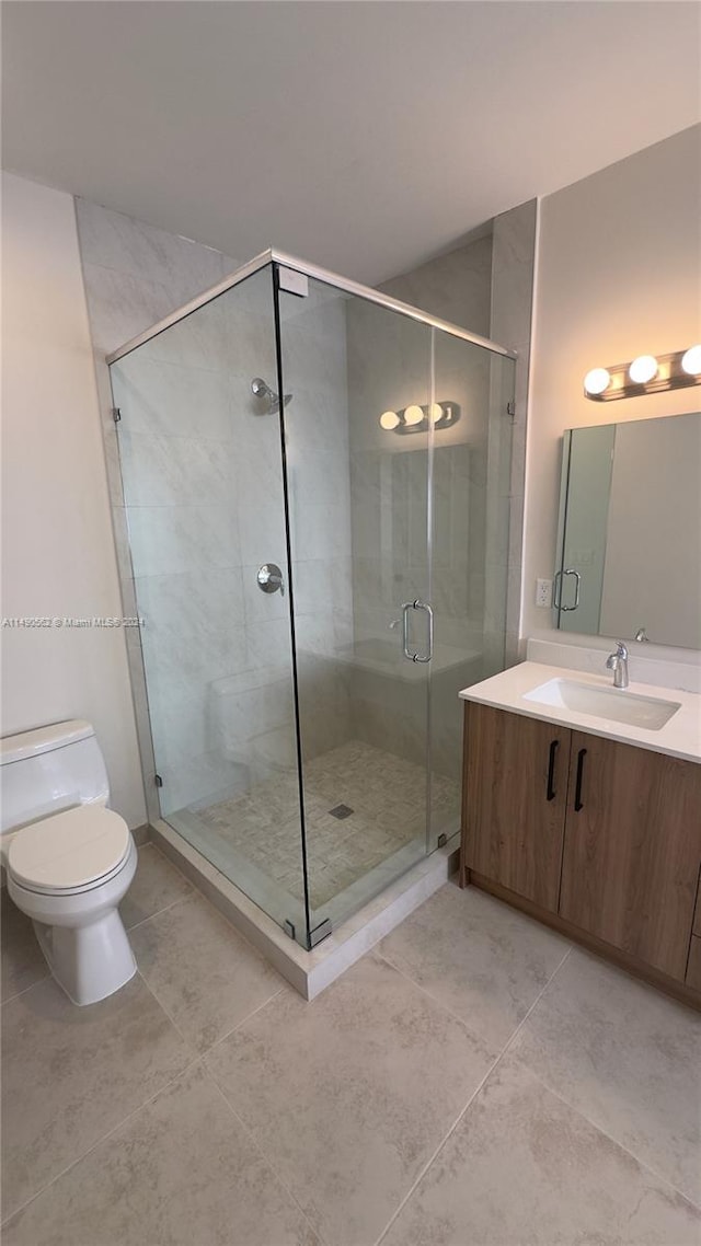 bathroom featuring vanity, tile flooring, a shower with shower door, and toilet