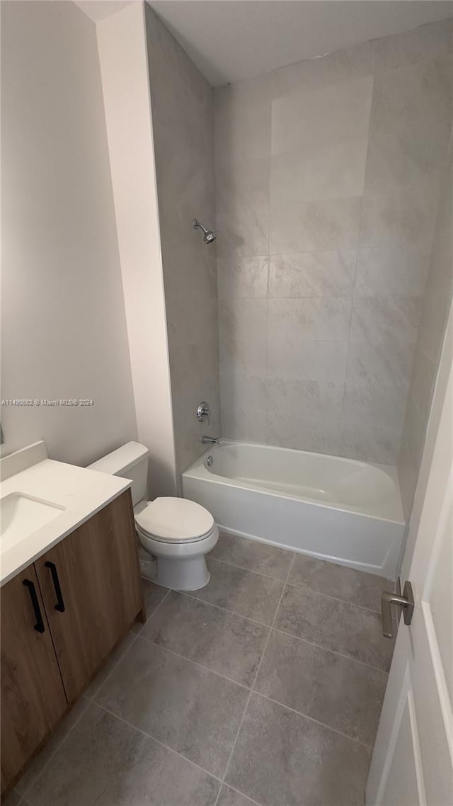 full bathroom featuring tiled shower / bath combo, vanity, tile floors, and toilet