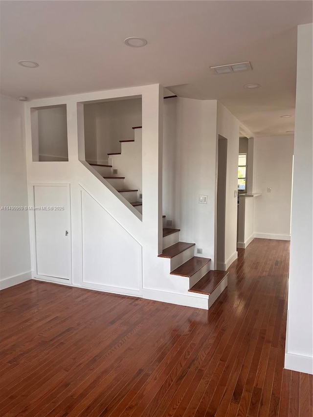 stairs with wood finished floors, visible vents, and baseboards