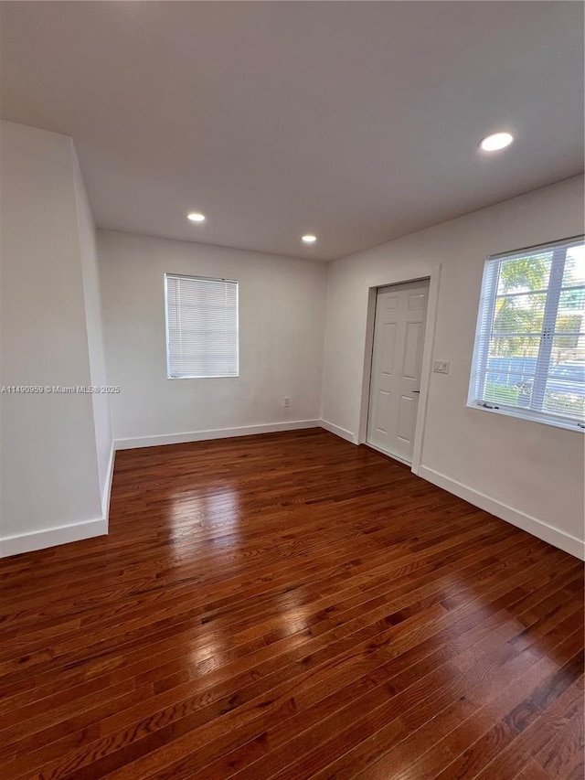 empty room featuring dark wood-style flooring, recessed lighting, and baseboards