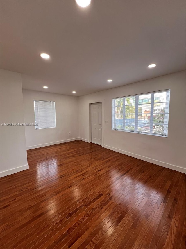 empty room featuring dark wood-style flooring, recessed lighting, and baseboards