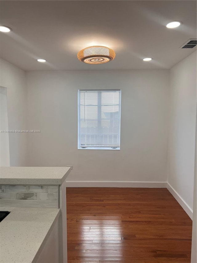 empty room with dark wood-style flooring, recessed lighting, visible vents, and baseboards