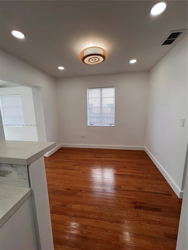 spare room with baseboards, visible vents, dark wood-style flooring, and recessed lighting